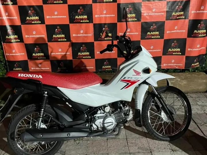 Honda Pop 110i ES 2025 branca e vermelha em frente ao painel da Aladdin Motos