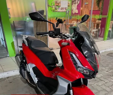 Urban 150 2025 vermelha estacionada em frente a uma loja
